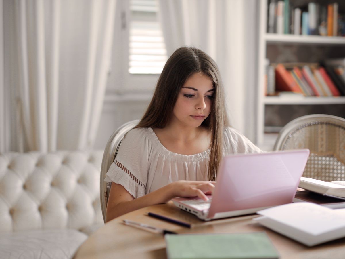 An A-Level student working intently at a bright desk — mature, focused preparation for university.